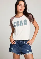 Remera blanca con mangas cortas color marrón y estampado frontal con la palabra "CIAO" en celeste con estrellas rosadas.
