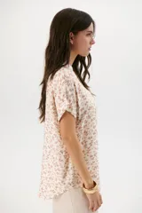 Blusa estampada con hojas color beige, escote en V y mangas cortas.