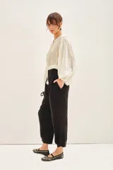 Pantalón sastrero color blanco, de tiro alto, con ajuste en el tobillo, bolsillos delanteros y traseros, y pinzas en el frente.