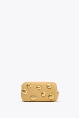 Bolso de mano tipo clutch color beige con apliques metálicos dorados. Incluye cadena metálica extraíble para usar como bandolera.