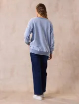 Buzo celeste de algodón con efecto lavado, escote en V, cuello, puños y ruedo acanalados y tajos laterales.