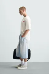 Camiseta blanca de corte holgado, cuello redondo y manga corta. Estampado frontal con la frase "Gourmet Groove LLC" en color fucsia.