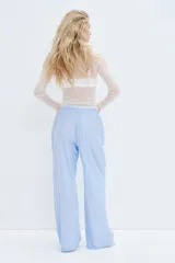 Pantalón de pijama celeste con rayas verticales blancas, de algodón suave, corte relajado, tiro bajo, cintura elástica, cierre decorativo con botones, piernas rectas y bolsillos laterales.