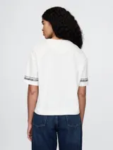 Remera corta color blanco con logo de Gap estampado en el frente y mangas cortas con detalle de rayas horizontales.