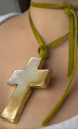 Colgante con dije de cruz de bronce con interior de nácar y tiento de gamuza color pistacho.