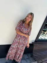 Vestido largo de fibrana y viscosa con estampado paisley en tonos rojos y negros. Tiene mangas cortas con punto smock en la espalda y escote en V.