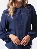 Blusa azul marino de manga larga con cuello redondo con detalle de broderie y cierre frontal con botones.