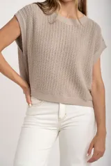 Chaleco de punto color beige con lurex, de corte recto y mangas cortas. Tejido calado con pequeños agujeros.