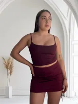 Conjunto de top y pollera color borgoña. El top es de breteles finos y la pollera es corta con frunces laterales y cordones ajustables.