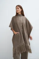 Ruana color crema de lana fina con flecos en el ruedo y bolsillos delanteros.