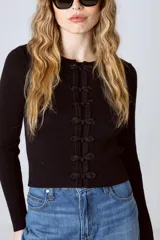Top negro de tejido de punto acanalado con mangas largas y cierre frontal con botones decorativos.