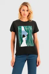 Remera negra con estampa de una mujer abriendo una cortina verde y blanca.