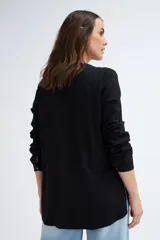 Blusa negra de manga larga con escote en V y cierre frontal con botones.