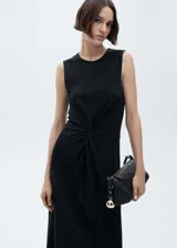 Vestido midi negro sin mangas con cuello redondo y detalle drapeado en la cintura.