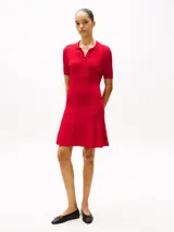 Minivestido rojo de tejido acanalado con cuello chomba, manga corta, corte evasé y botonadura dorada con logo grabado.