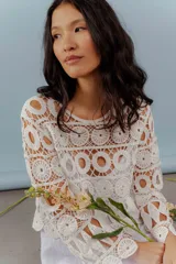 Blusa beige de hilo calado con mangas largas y cuello redondo.