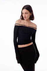 Top negro con cuello bote, hombros descubiertos y mangas largas.