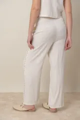 Pantalón de lino color crudo con bordado floral color camel en el ruedo y costados. Tiene bolsillos laterales y cintura elástica.