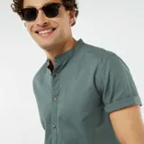 Camisa verde de manga corta con cuello mao y cierre frontal con botones.