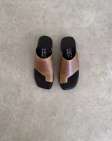 Sandalias de cuero vacuno color marrón claro, con base negra y diseño minimalista.