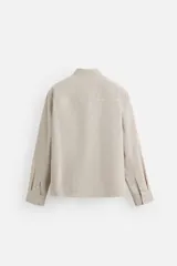Camisa regular fit confeccionada en tejido con mezcla de algodón. Color beige con finas rayas verticales blancas. Cuello italiano, manga larga con puños abotonados, bolsillo de parche en el pecho y cierre frontal con botones.