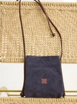 Bandolera pequeña de cuero azul con correa larga de cuero marrón y logo bordado en naranja.