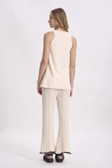 Pantalón de punto color crema, de corte acampanado y cintura alta.