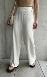 Pantalón de lino color crudo, de corte ancho y largo, con botones decorativos en la cintura.