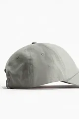 Gorra gris de lino y algodón con ojales bordados en la parte superior y trabilla ajustable con hebilla de metal atrás.