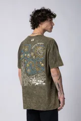 Remera de hombre color gris oscuro con efecto gastado (snow wash), corte semi-oversize y un pequeño estampado circular en el pecho que simula una obra de arte.