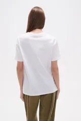 Remera blanca de algodón, de manga corta y cuello redondo. Presenta un detalle bordado y calado en el hombro derecho con motivos florales.