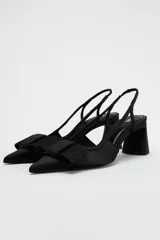 Zapato destalonado negro con tacón ancho y tira trasera. Detalle de lazo en la parte delantera.
