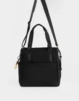 Cartera shopper negra de tela deportiva con doble asa corta estampada, correa regulable y desmontable, cierre superior con puller de goma y charm lateral.