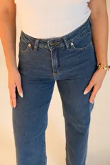 Jean wide leg de tiro alto, color azul oscuro. Tiene dos bolsillos redondeados en la cadera en la parte delantera y dos bolsillos en la parte trasera. Cuenta con botón metálico, cremallera y terminación de ruedo desflecado.