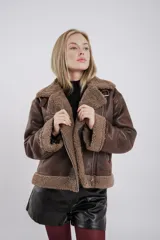 Chaqueta de piel sintética en color marrón con forro de corderito y detalles de hebilla.