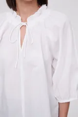 Blusa blanca de algodón con escote en V con lazos, mangas 3/4 abullonadas y corte holgado.