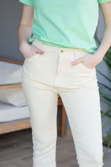 Pantalón de jean color crema, tiro medio alto, corte bootcut y calce elastizado.