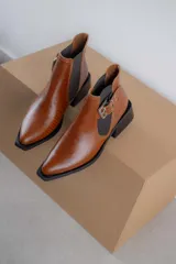 Botines Chelsea color beige con elásticos laterales negros, punta cuadrada, detalle de hebilla lateral y tacón bloque bajo.