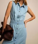 Vestido midi de jean celeste, sin mangas, con cuello camisero, abotonado al frente y con lastex en la cintura.