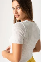 Remera blanca de punto con textura acanalada, cuello redondo y mangas cortas.