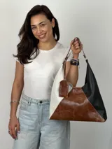 Bolso tipo hobo de cuero con diseño geométrico tricolor: blanco, marrón y negro.