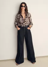 Camisa de manga larga con estampado abstracto en tonos marrones y blancos, cuello camisero y cierre frontal con botones.