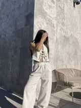 Pantalón largo de tiro alto con estampado a rayas verticales beige y blanco.