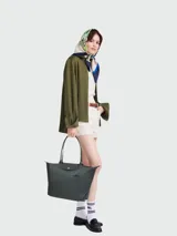Bolso tote Longchamp modelo Le Pliage Green L, color marrón chocolate, confeccionado en lona de nylon reciclado con detalles en cuero ruso color marrón oscuro. Cuenta con cierre de cremallera y botón a presión, asas cortas para llevar al hombro y es plegable para facilitar su almacenamiento.