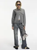Sobrecamisa gris con broches metálicos en la parte delantera, bolsillo con solapa y cuello camisero.