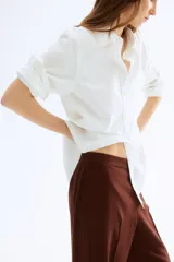 Pantalón ancho color marrón chocolate, de tiro alto con elástico en la parte posterior de la cintura y cierre oculto con corchete en un lado. Presenta bolsillos laterales discretos y piernas amplias con pliegues adelante y atrás.
