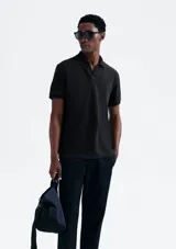 Camisa polo de piqué negro con cuello clásico y tapeta de dos botones.