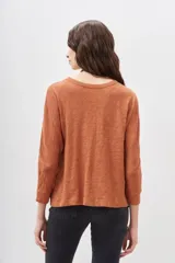 Remera de manga larga color terracota con textura jaspeada, confeccionada en algodón peruano. Presenta un calce holgado con mangas que se ensanchan debajo del brazo y se ajustan en la muñeca.