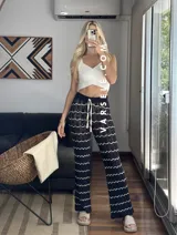 Pantalón de hilo color marrón con rayas horizontales blancas, corte holgado y cintura con cordón ajustable.