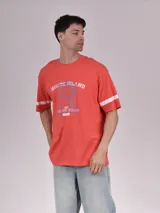 Remera roja de corte holgado con estampado frontal que incluye texto y dibujo. Tiene mangas cortas con dos rayas blancas.